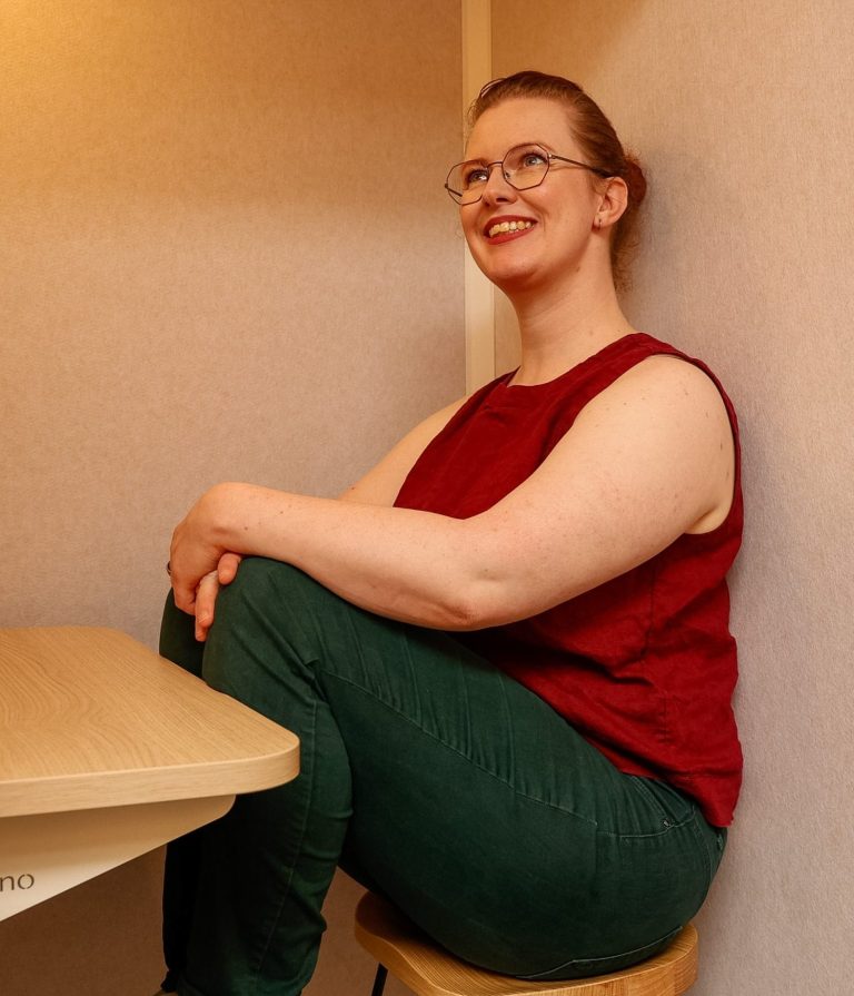 Katharina Budde Katharina ist eine weiße Person mit rotbraunen Haaren. Sie trägt ein rotes Top und eine grüne Hose, dabei schaut sie nach oben in die Ferne.