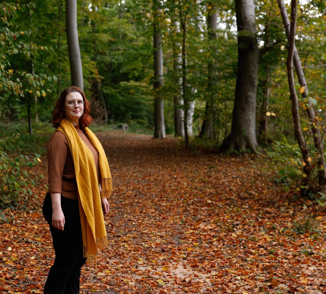 Weg zu mir Katharina steht auf einem herbstlichen Waldweg und schaut sich zu dir um
